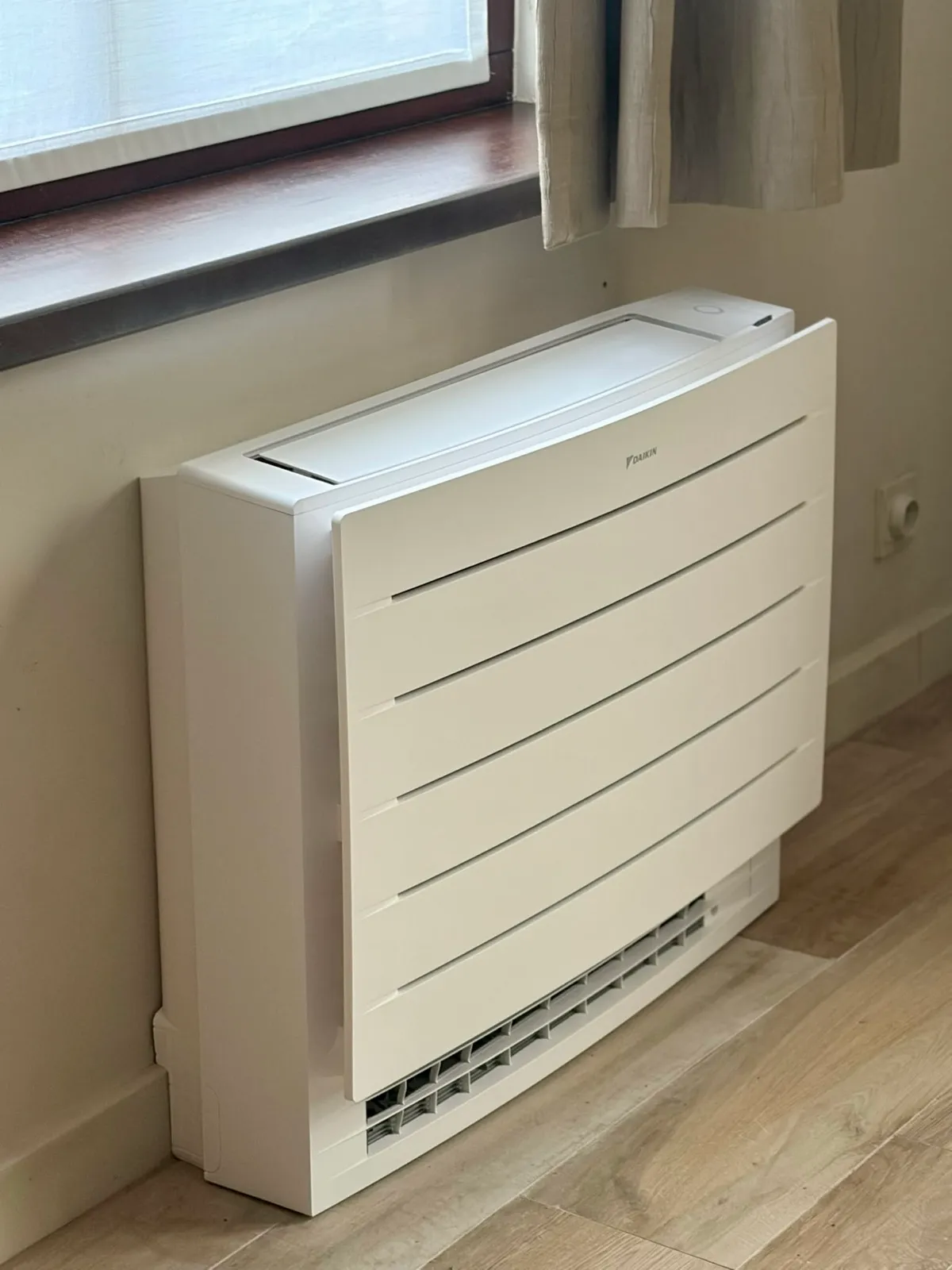 Floor-standing air conditioning unit installed under a window