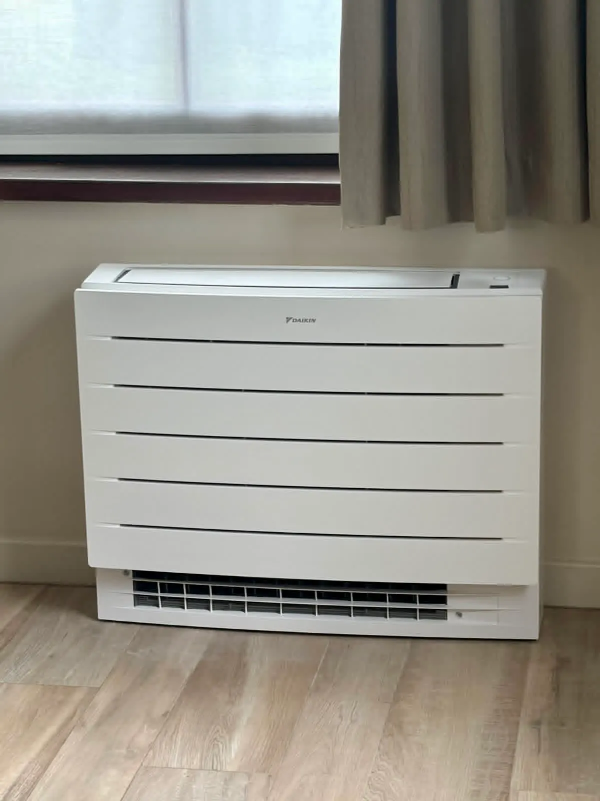 Floor-standing air conditioning unit installed under a window